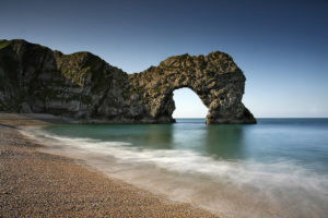 Long exposure of Durdle Door during the day captured the movement of a breaking wave in the foreground.