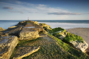 A sea groyne at Hengistbury Head at sunset creates a lovely coastal scene.